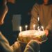 two people holding cake with lit candles